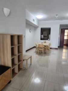 Open-concept living area with a wooden dining table and chairs, a tall cubby shelf, and glossy tiled flooring.