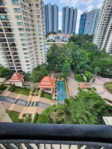 Bird's-eye view of a residential complex with a central rectangular pool, landscaped gardens, and tall beige and gray apartment towers.