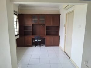 Dark wood built-in desk and shelving unit along a back wall, with a swivel chair in front in a bright tiled room.