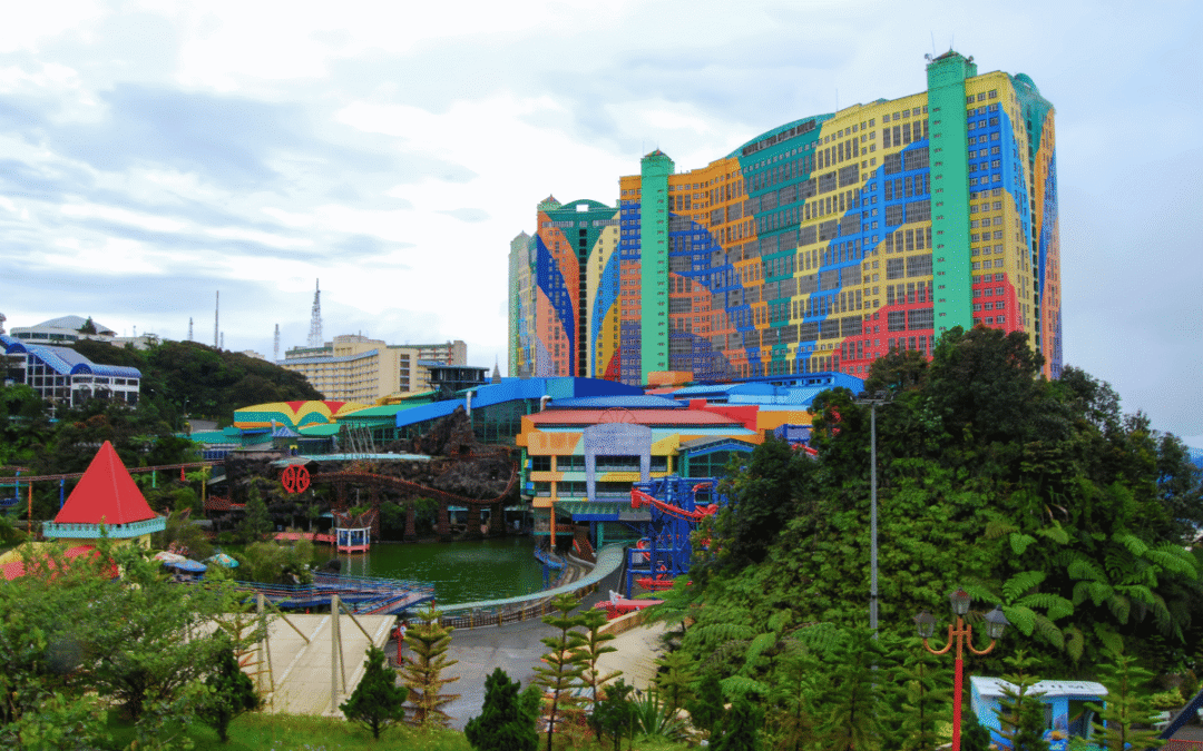 Rainbow-colored multi-tower building at a theme park, with water rides and green landscaping in foreground.