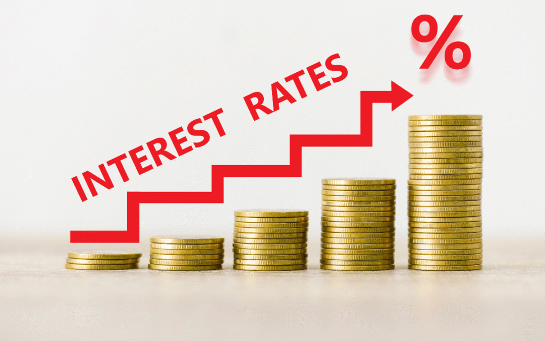 Stacks of gold coins increasing in height with a red stair-step arrow and the text INTEREST RATES, illustrating rising rates.
