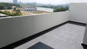 Rooftop balcony with gray tiled floor and white low boundary wall overlooking a river and distant cityscape.