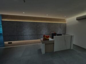 Modern reception desk in a minimalist office lobby with dark stone wall panels and warm backlighting.