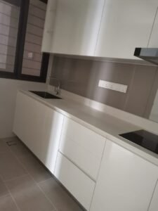 Modern white kitchen with a sleek countertop, sink on the left, and a built-in induction stove on the right; gray backsplash and upper cabinets.